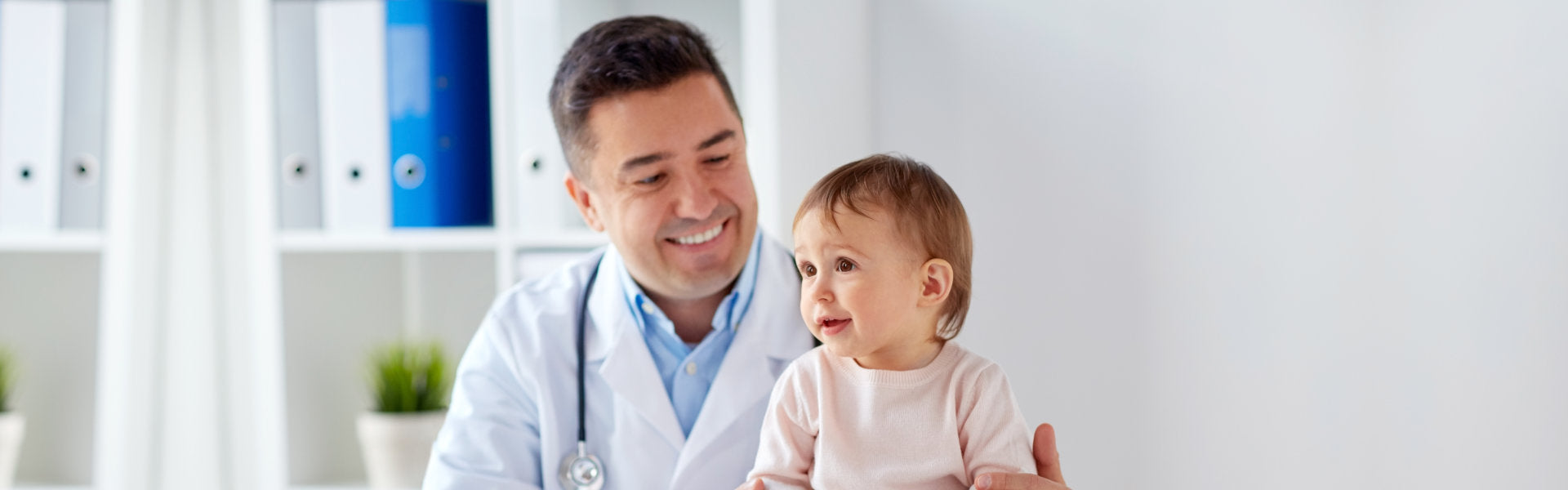 Happy doctor or pediatrician with baby at clinic